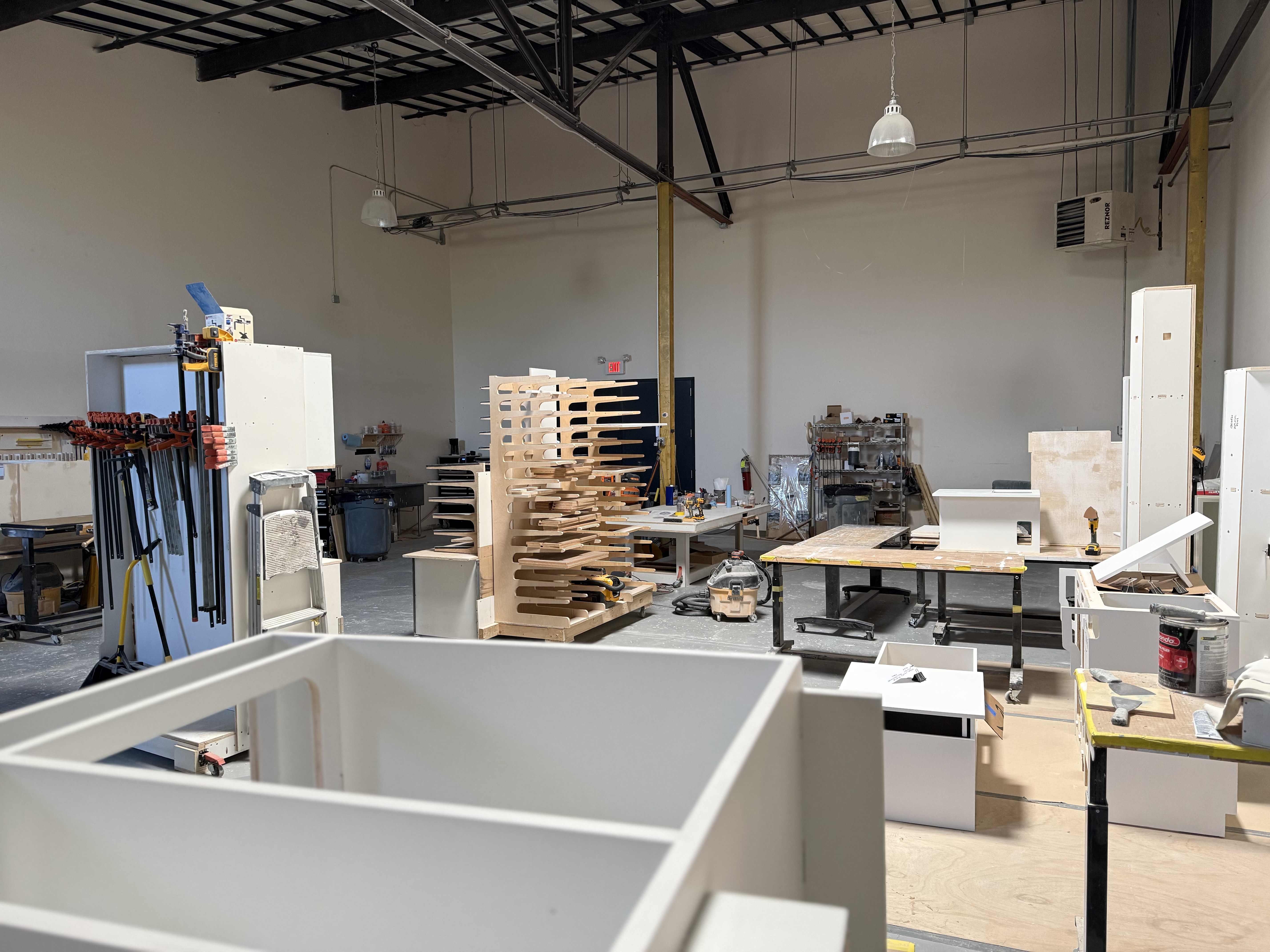 Cabinet shop area with assembled van cabinetry and work tables.