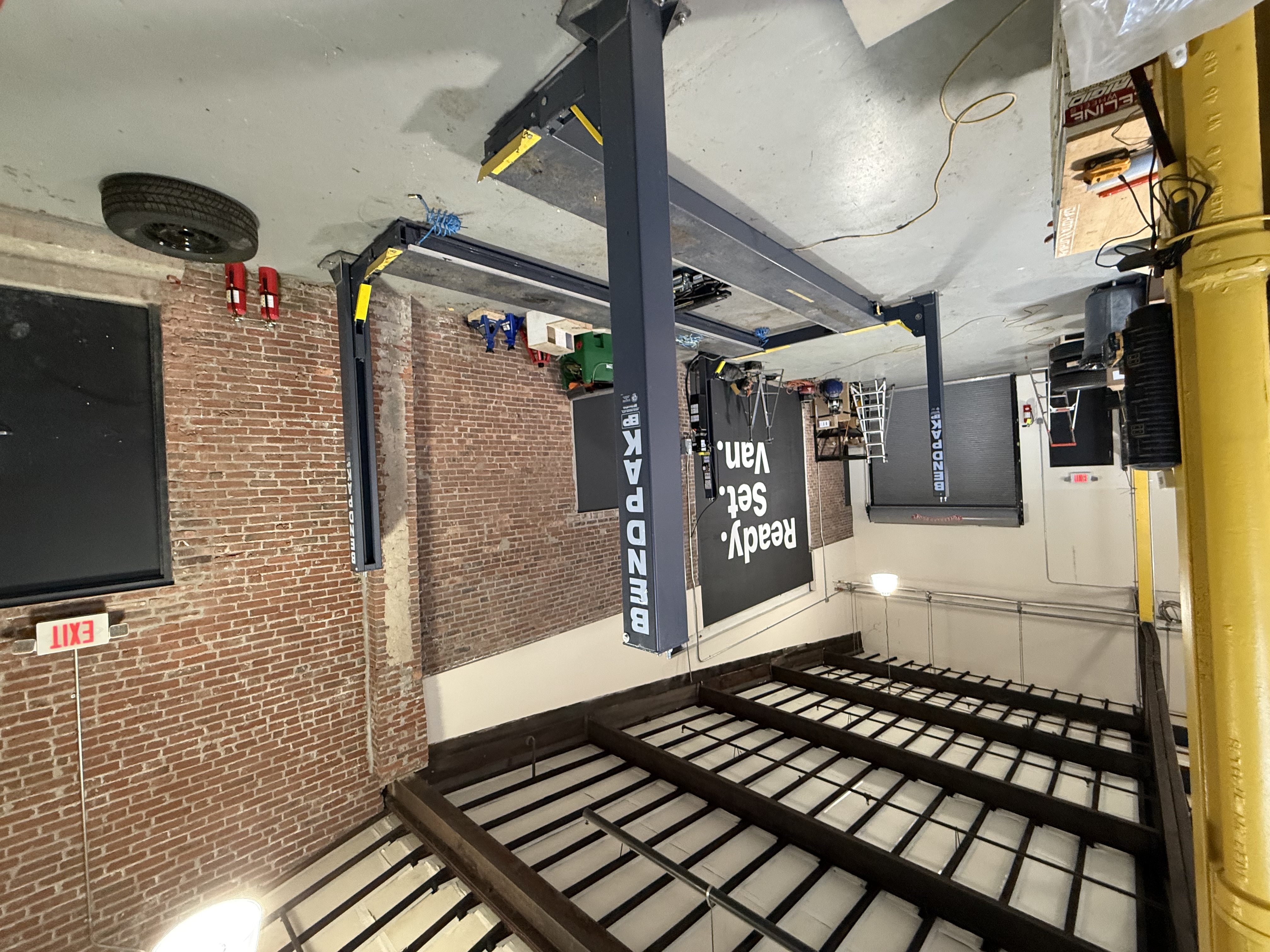 Lift room with BendPak lifts, brick walls, and high-bay shop structure.